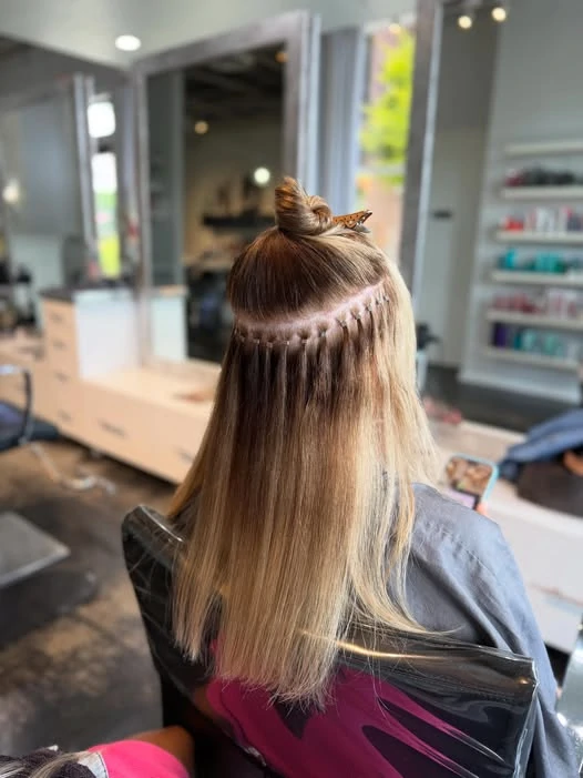 Close-up of bead placement during a hair extension installation at Michele Coulter Salon